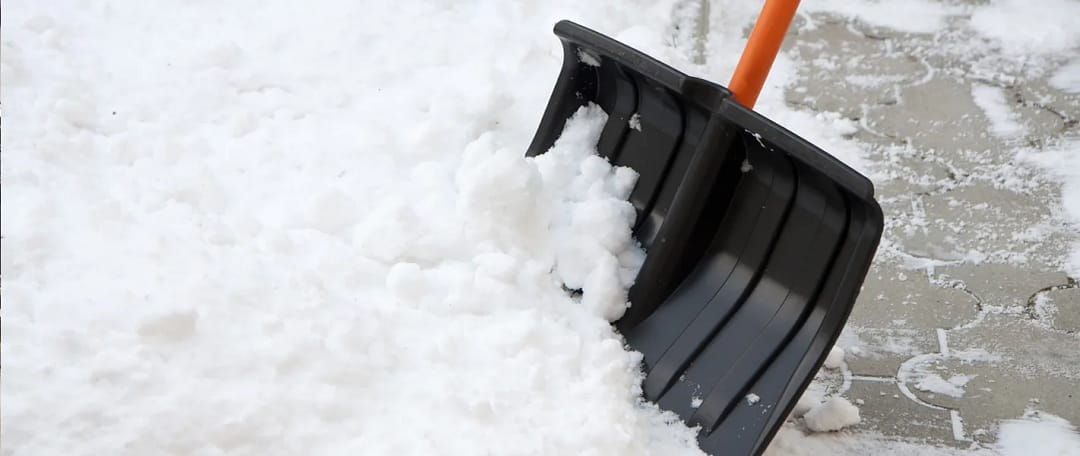 Shoveling snow with a plastic shovel.