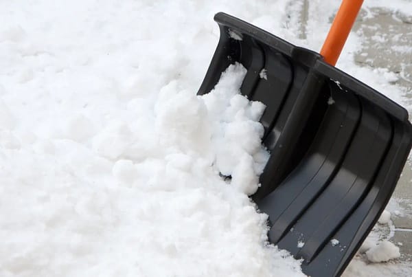 Shoveling snow with a plastic shovel.