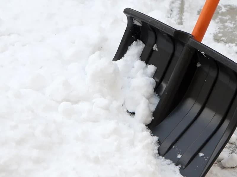 Shoveling snow with a plastic shovel.