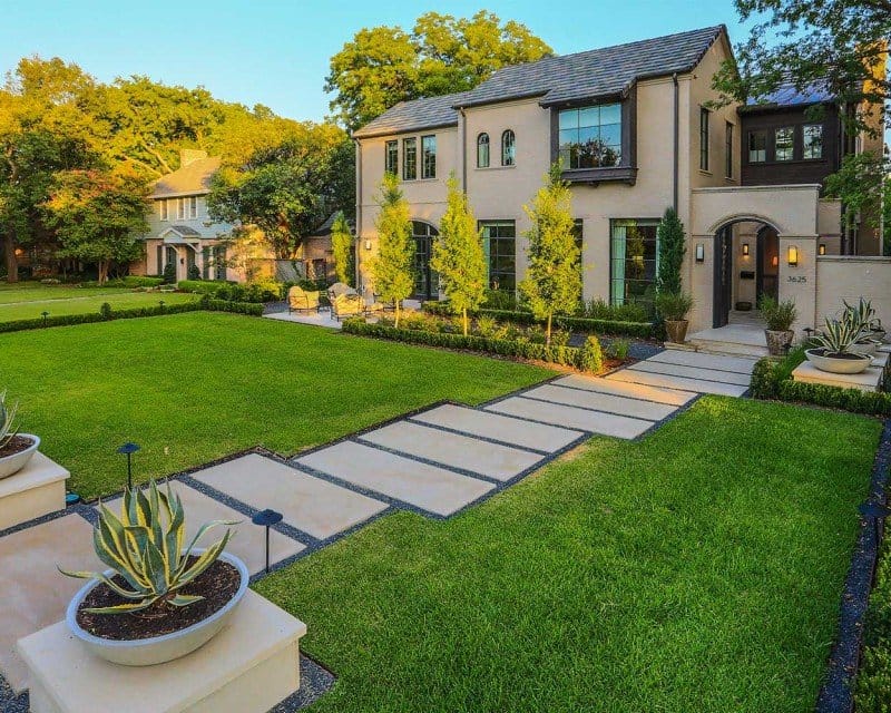 Modern home with a manicured lawn and stone walkway.